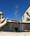 Garden fountain with solar bird bath fountain pump kit with 4 nozzle heads in statue decor, water spray in sunlight.