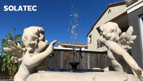 Garden fountain with solar bird bath fountain pump kit with 4 nozzle heads in statue decor, water spray in sunlight.