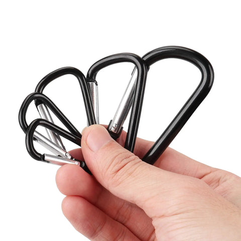 Hand holding black aluminum carabiner clip snap hook keychain set with multiple sizes