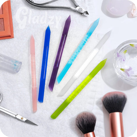 Glass Cuticle Pusher Manicure Stick with slanted side and pointed end in assorted colors on a towel, pro-grade tool.