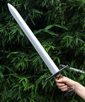 Hand holding Two Pack 25 Inch Medieval Viking PU Foam Sword For Adults Costume Weapon Safe Soft Foam Larp Prop against foliage