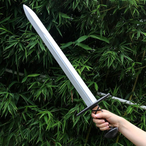 Hand holding Two Pack 25 Inch Medieval Viking PU Foam Sword For Adults Costume Weapon Safe Soft Foam Larp Prop against foliage
