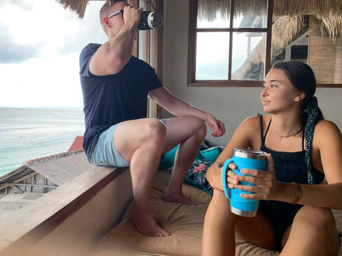 Two people with stainless steel tumblers, one with a Protective Silicone Tumbler Sleeve With Handle for 20 oz mugs, enjoying a scenic view.