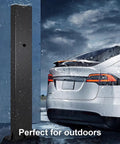 Badass EV Charger Cable Holder And Weatherproof Station Box For Outdoor Parking Spots Electric Vehicle Cord Protector Heavy Duty Carbon Steel Quick Install Rack For Your Rig Garage Setup White, shown in rain by a parked car.