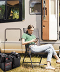 Hardcore 12V Smart Battery Box With Pd Quick Charge Port Anderson Plug Digital Voltmeter Circuit Breaker For Rv Van Suv Overland Grind And Camp Setup beside a woman relaxing outside a camper.