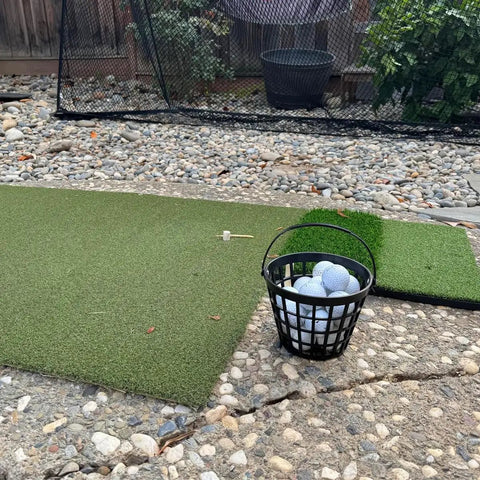 Portable Golf Ball Basket With Handle Holds Up To 50 Balls, Black Ball Bucket on backyard mat with net in view