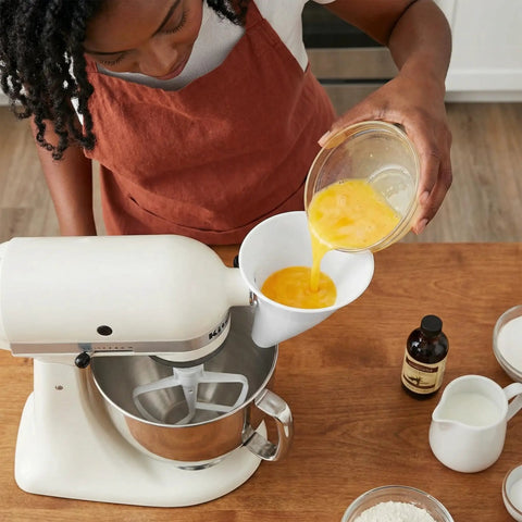 Mess-Free Flour Funnel Attachment for Stand Mixers with Extended Splash Guard being used to pour eggs into mixer bowl.