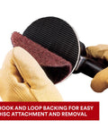 2 Inch Nonwoven Surface Conditioning Disc Medium Grit For Cleaning Finishing Blending And Light Deburring Open Web Material Runs Cooler Resists Loading And Will Not Gouge 25 Per Carton with hook and loop backing being attached to tool by gloved hand.