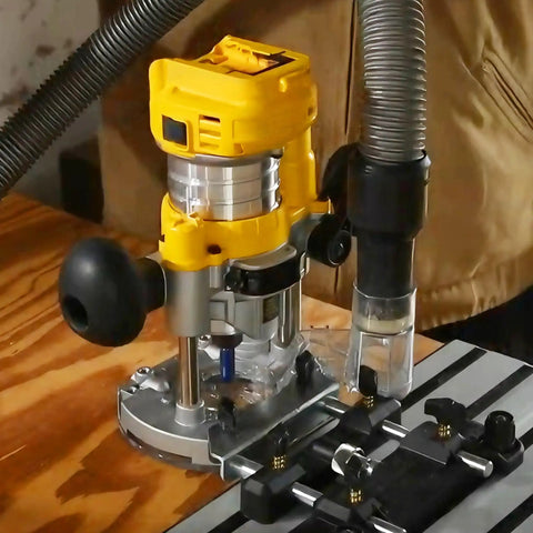 DNP616 Dust Collection Adapter attached to DWP611 Compact Router on a plunge base with vacuum hose on workbench.