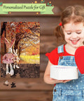 Child smiles holding heart box next to completed puzzle featuring dolls under autumn trees, Six Pack Sublimation Blank Jigsaw Puzzles White A5 Size, 80 Pieces Each, DIY Transfer Friendly for Heat Press Printing and Crafts