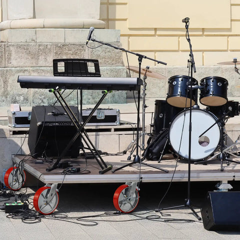 Heavy Duty Eight By Two Inch Industrial Casters Polyurethane And Steel Wheels Six Thousand Pound Capacity Built Tough For Shop Carts And Utility Dollies Rolls Easy No Sweat Swivel Lock Brakes Pack Of Four on a stage platform with musical equipment.