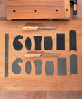 Top Shelf Six Piece Cabinet Scraper And Burnisher Kit With Blue Spring Steel Blades plus hardened high speed steel sharpening rod arranged on wood.