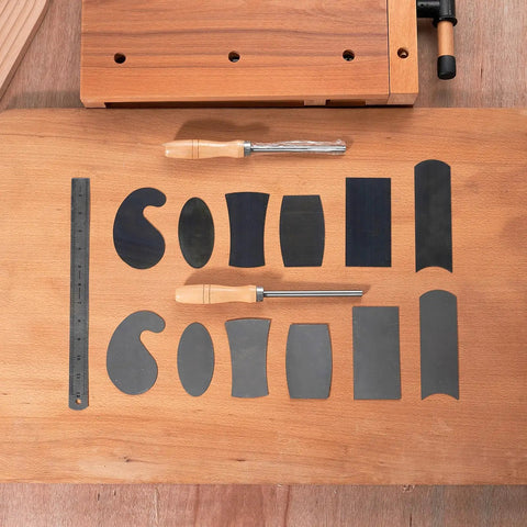 Top Shelf Six Piece Cabinet Scraper And Burnisher Kit With Blue Spring Steel Blades plus hardened high speed steel sharpening rod arranged on wood.