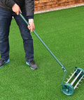 Person using a Rolling Lawn Aerator 18 Inch With Heavy Duty Spiked Tines For Deep Soil Aeration Manual Push Rotary Tool With 41 Inch Handle