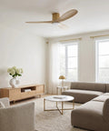 Slick Fifty Two Inch Hugger Ceiling Fan In Burnished Brass With Three Washed White Oak Blades bringing a cozy vibe to a modern living room.