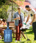 Outdoor scene with a Two Pack Electric Portable Five Gallon Water Dispenser With Micro USB Charging Water Bottle Pump next to a grill.