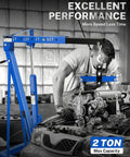 Blue 2-ton hydraulic engine hoist crane with folding boom and 6 locking wheels lifting a car engine in a garage