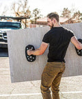 Man using Grab On Pro Electric Suction Cup Lifter to hold drywall sheet outdoors, showcasing its heavy-duty lifting capability.