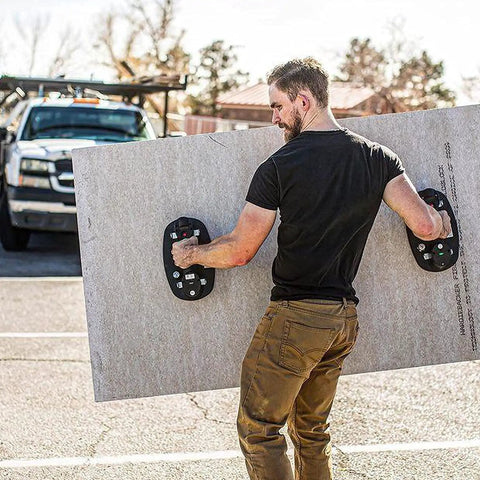 Man using Grab On Pro Electric Suction Cup Lifter to hold drywall sheet outdoors, showcasing its heavy-duty lifting capability.
