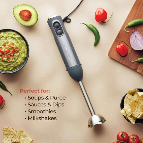 500 Watt Electric Hand Blender With Turbo Boost And Sharp Stainless Steel Blades For Smoothies Soups Purees And Baby Food Detachable Base Grey on a table with avocado and soup.