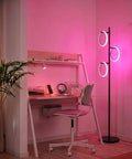 RGB Color Changing Floor Lamp With Tall Tree Design, Modern Standing Lamp For Living Room, Bedroom And Office, 3 LED Lights, Matte Black Finish, Smooth RGB Gradient For Reading, Ambience And Vibe illuminating a pink-lit workspace.