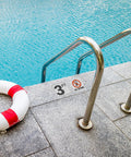 Poolside view with a 3ft depth sticker and no diving sign on the deck near a ladder and lifebuoy.