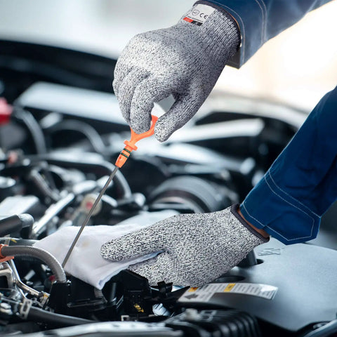 Person wearing grey Level 5 cut resistant kitchen gloves checking car engine with screwdriver, showcasing grippy flexible grip.