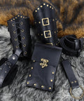 Badass Renaissance Belt Pouch Set With Detachable Corset Strap Soft Leather Bracers Vintage Coin Purse And Utility Hook Strap For Ren Faire Larp Gear That Legit Slaps At The Fair displayed on a fur background, showcasing black leather bracers and pouch.
