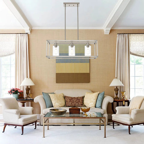 Rectangle Chandelier With 3 Lights In Brushed Nickel Finish hanging over a living room with sofas and a glass coffee table.
