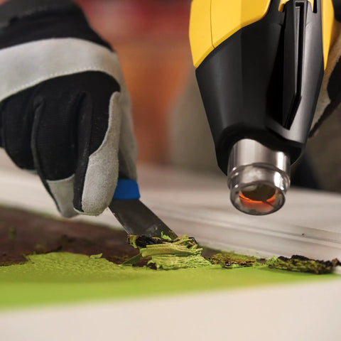 FURNO 700 Digital Heat Gun With 2 Nozzles removes paint as person scrapes paint from wood surface, emphasizing adjustable temperature control.