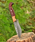 Custom Handmade Damascus Fixed Blade Knife 10 Inch with Rosewood and Olive Wood Handle embedded in tree stump outdoors.