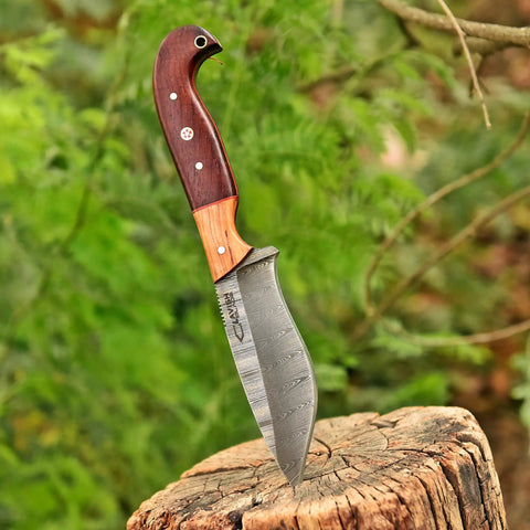 Custom Handmade Damascus Fixed Blade Knife 10 Inch with Rosewood and Olive Wood Handle embedded in tree stump outdoors.