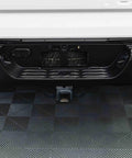 Rear view of a white SUV showing a black bumper and trailer hitch receiver.