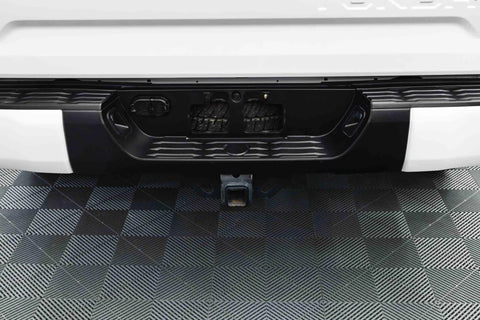Rear view of a white SUV showing a black bumper and trailer hitch receiver.