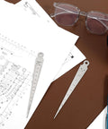 Two stainless steel taper gauge rulers, double-sided, 1-15 mm and 5/8 in ranges, on blueprint with glasses.