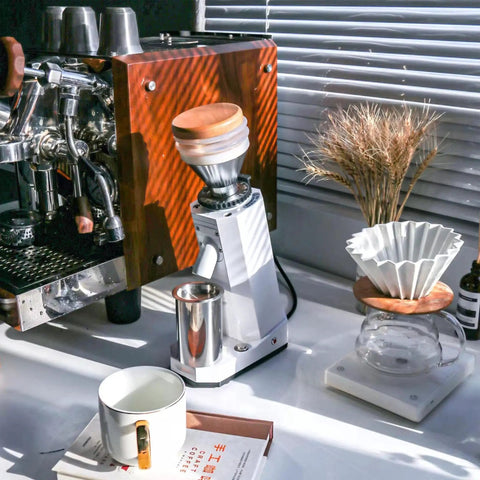 Kickstart Your Daily Grind With This Rock Solid Electric Coffee Grinder Featuring 40Mm Conical Titanium Burrs 19 Straight Forward Settings And A Generous 75G Bean Hopper For Fresh Bold Sips And Zero Hassle Cleanup Guaranteed, placed next to an espresso machine and coffee accessories.