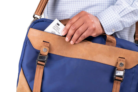 Person placing Notebook Screen Cleaning Wipes For Electronics, Non Abrasive Premoistened Wipes into a blue and tan bag.