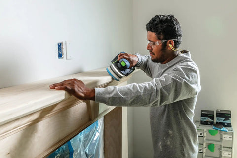 Man sanding wooden molding using Granat Profile Fine 5 Inch 125 mm Sanding Discs 10 Pack For Contours Moldings And Curved Surfaces.