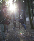 Child using 200 Ft Zip Line Kit With Adjustable Harness And Bungee Brake System For Backyard Fun in a forest setting
