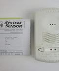 Front view of 12 24V 4 Wire System Monitored Carbon Monoxide Detector With RealTest Technology next to instruction manual.