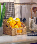 Set Of 2 Scalloped Wicker Storage Baskets With Handles For Food Organization, filled with lemons and oranges on a kitchen counter.