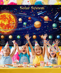 Children celebrating under Giant Solar System Poster Banner For Space Themed Parties And Classroom Decor, 72.8 by 43.3 inches.
