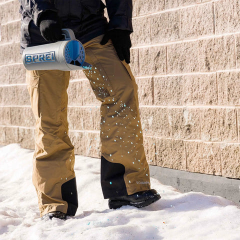 Person using Spot Spreader 80 Oz Handheld Grab-And-Go Dispenser for salt on snowy ground with multi-size openings.