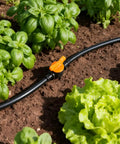 Quarter inch barbed drip irrigation system with orange valve in garden with lettuce, part of 230 Piece All In One Kit.