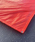Corner detail of Dang Tough Insulated Concrete Blanket 6X25 Ft with grommet, heavy-duty red waterproof cover.