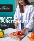 Wood cutting board on kitchen counter with a person slicing a red bell pepper; Blue Ridge Mountain Gifts logo visible.