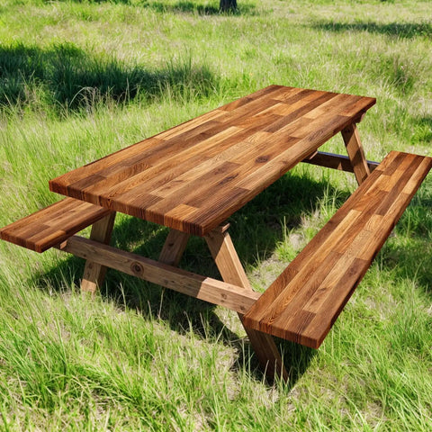 Wooden picnic table with attached benches in grassy outdoor setting