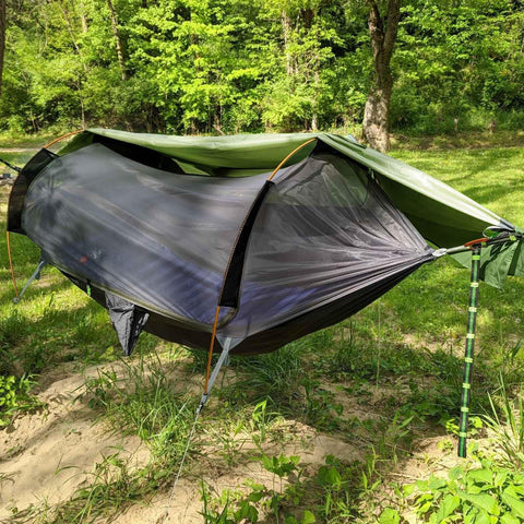 3 In 1 Camping Hammock Tent With Mosquito Net And Rain Fly Lightweight Waterproof Portable Sleeping Hammock For Backpacking Hiking Or Outdoor Adventures Includes Tree Straps And Easy Setup set up in a forest, showing mosquito net and rain fly.