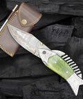 Fish Style Copper Damascus Folding Knife With Ladder Pattern Blade, Brass Engraved Handle, Leather Sheath on wood surface