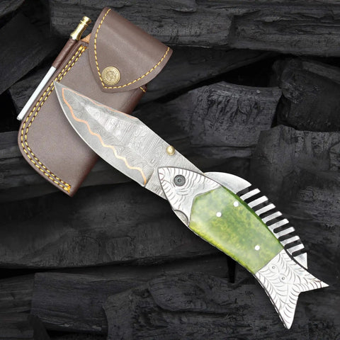 Fish Style Copper Damascus Folding Knife With Ladder Pattern Blade, Brass Engraved Handle, Leather Sheath on wood surface